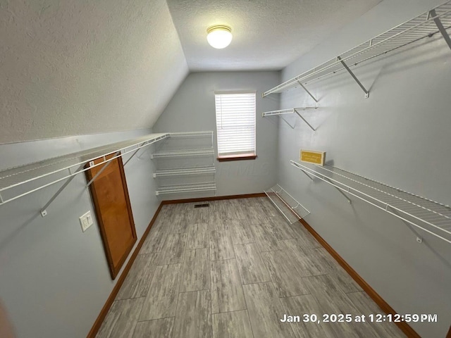 walk in closet with lofted ceiling and light hardwood / wood-style flooring