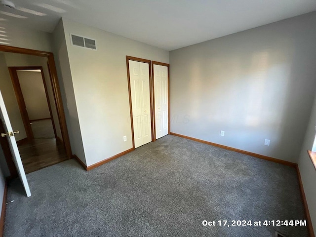 unfurnished bedroom featuring dark colored carpet and a closet