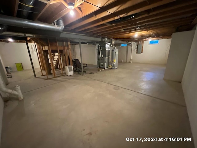 basement with electric panel, heating unit, and gas water heater