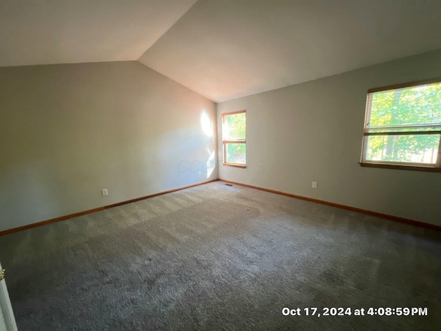 carpeted empty room with lofted ceiling