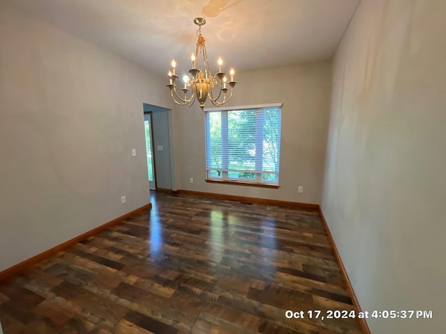 empty room featuring dark hardwood / wood-style floors and a notable chandelier