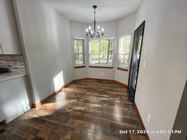 unfurnished dining area featuring plenty of natural light, dark hardwood / wood-style floors, and a chandelier