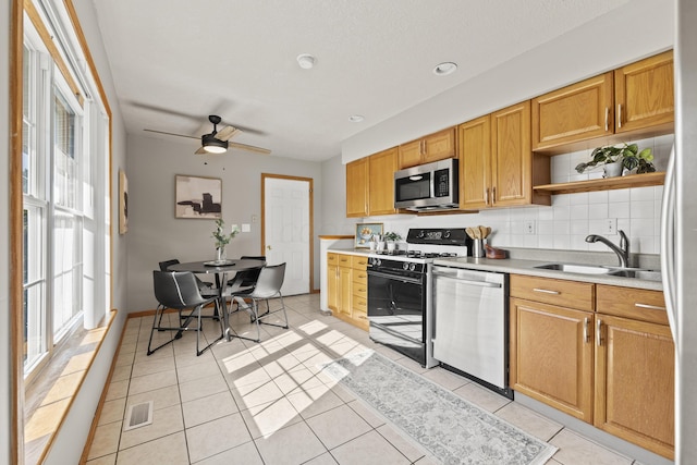 kitchen featuring stainless steel appliances, ceiling fan, backsplash, light tile patterned floors, and sink