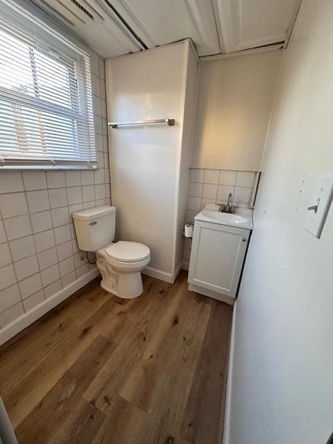 bathroom featuring wood-type flooring, tile walls, vanity, and toilet