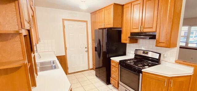 kitchen featuring tasteful backsplash, sink, black refrigerator with ice dispenser, and stainless steel range with gas stovetop