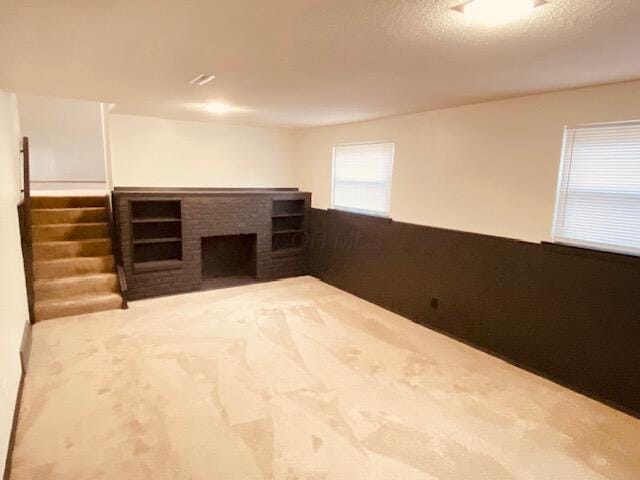 carpeted empty room featuring a brick fireplace and a textured ceiling