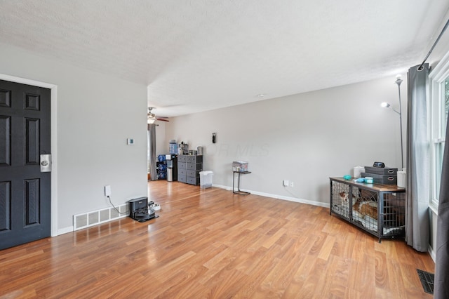 foyer entrance featuring ceiling fan, light hardwood / wood-style flooring, and a textured ceiling