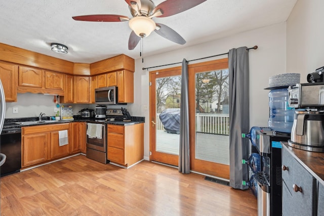 kitchen with sink, light hardwood / wood-style flooring, a textured ceiling, ceiling fan, and stainless steel appliances