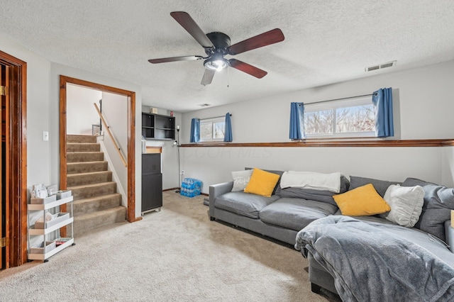 carpeted living room with ceiling fan and a textured ceiling