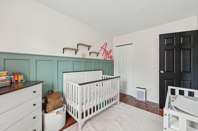 bedroom with hardwood / wood-style floors, a closet, and a crib