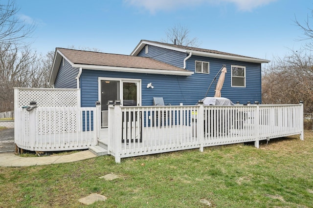 rear view of property featuring a wooden deck and a lawn