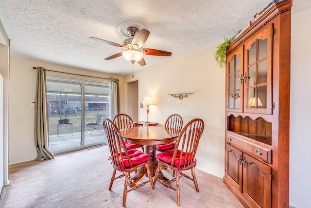 dining room featuring light carpet, a textured ceiling, and ceiling fan