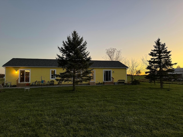 back house at dusk with a lawn