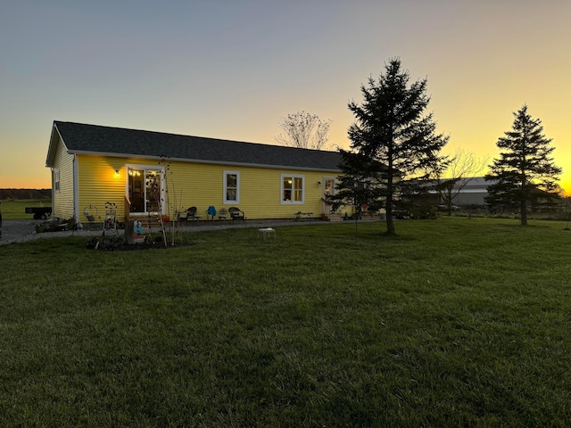 back house at dusk with a lawn