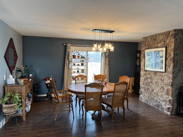 dining area with a textured ceiling, dark wood-type flooring, and a chandelier