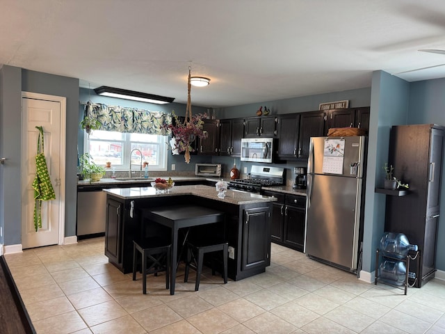 kitchen featuring a kitchen island, appliances with stainless steel finishes, sink, a kitchen breakfast bar, and light stone countertops