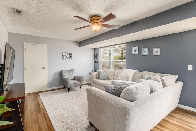 living room featuring hardwood / wood-style floors, a textured ceiling, and ceiling fan