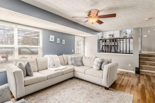 living room featuring wood-type flooring, ceiling fan, and a textured ceiling