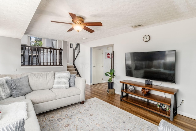 living room featuring wood-type flooring, ceiling fan, and a textured ceiling