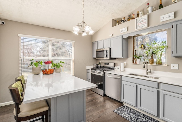 kitchen featuring gray cabinets, pendant lighting, sink, stainless steel appliances, and a textured ceiling