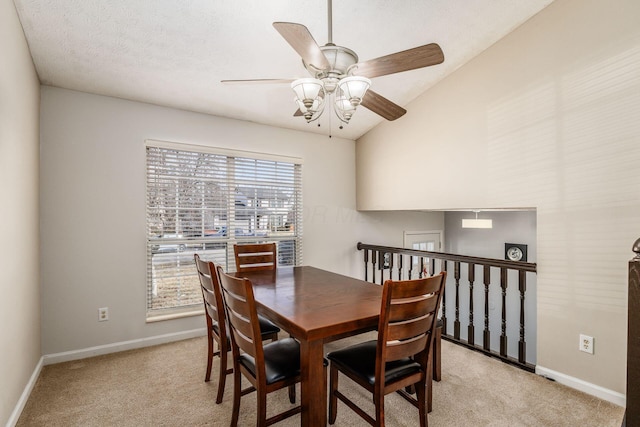 dining area featuring ceiling fan, vaulted ceiling, light carpet, and a textured ceiling