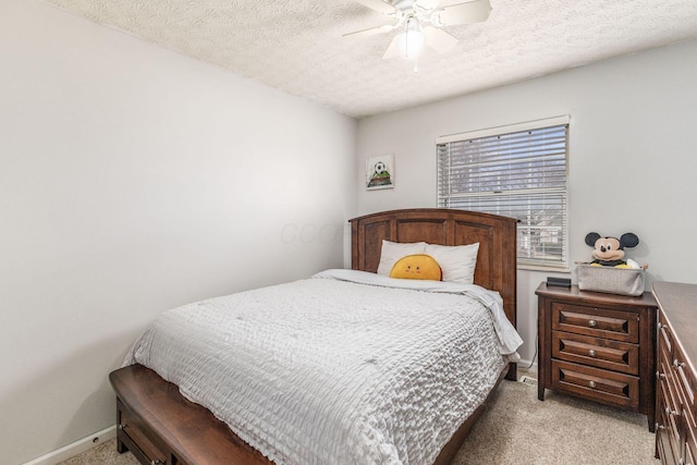 bedroom with ceiling fan, light colored carpet, and a textured ceiling