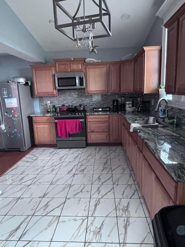 kitchen featuring sink, appliances with stainless steel finishes, dark stone countertops, hanging light fixtures, and tasteful backsplash