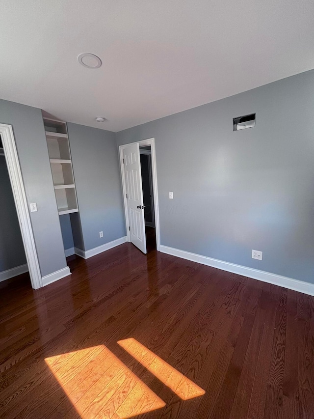 unfurnished bedroom featuring dark wood finished floors and baseboards