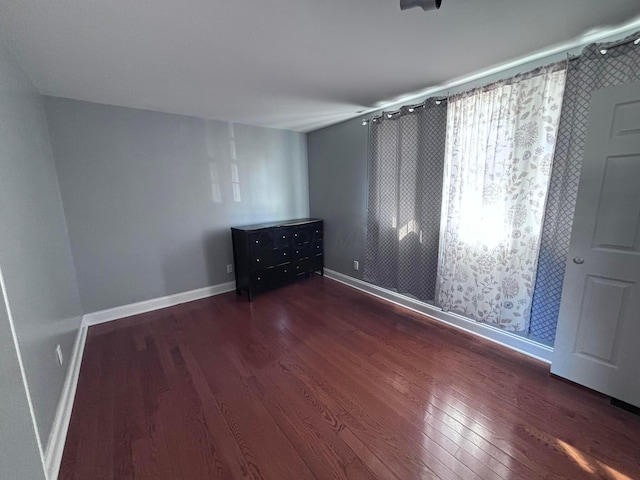 unfurnished bedroom featuring wood finished floors and baseboards