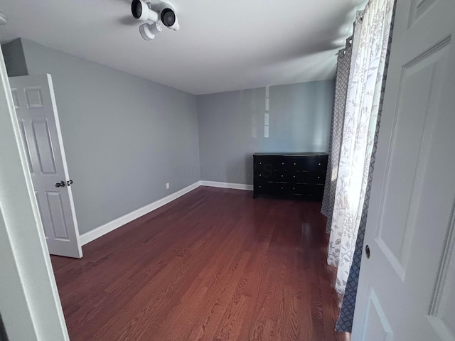 unfurnished bedroom with baseboards and dark wood finished floors