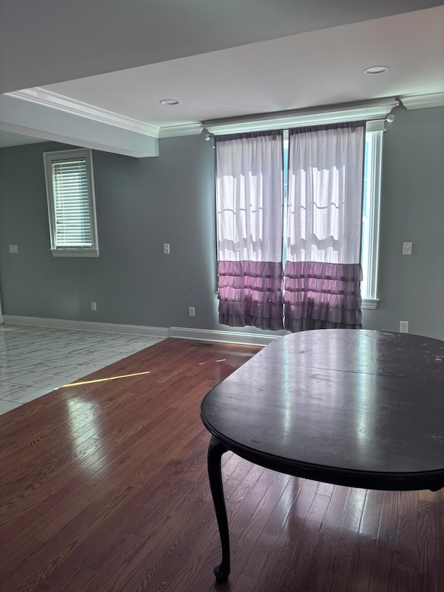 unfurnished dining area featuring wood finished floors, baseboards, and ornamental molding