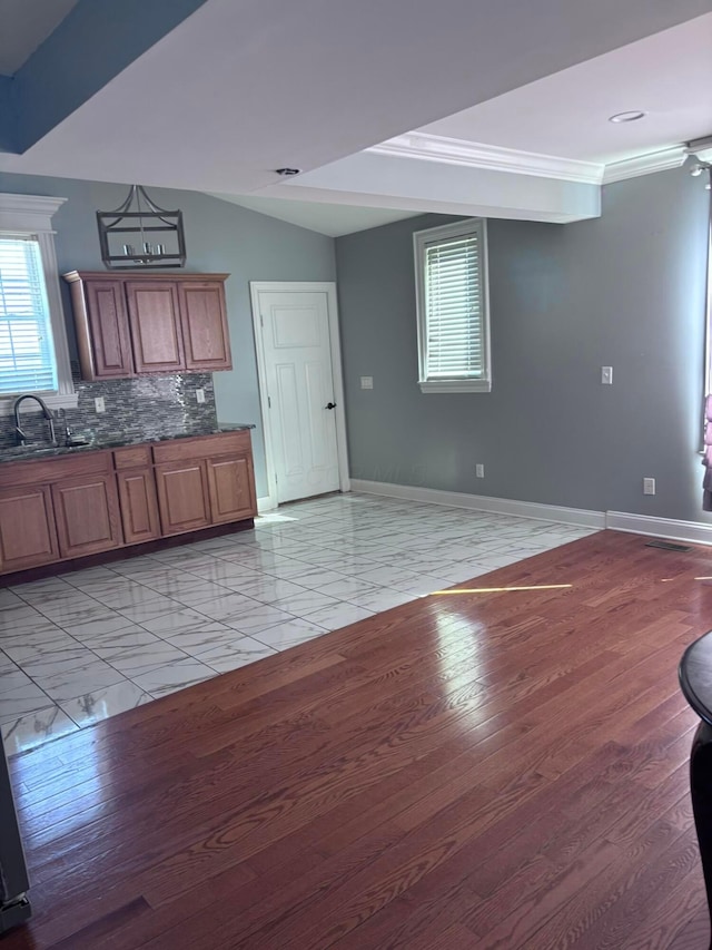 kitchen featuring a sink, baseboards, tasteful backsplash, and a wealth of natural light