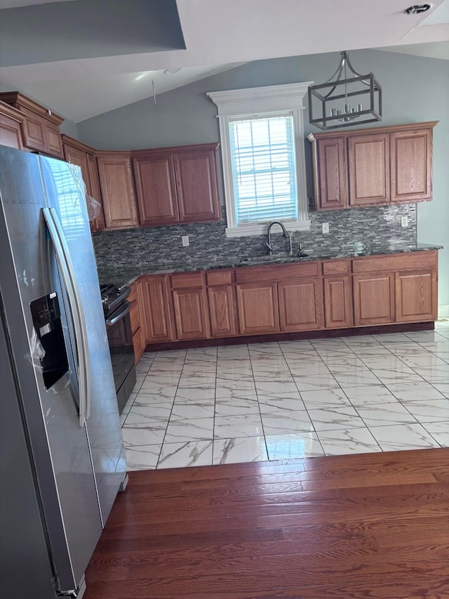 kitchen with brown cabinets, stainless steel fridge with ice dispenser, a sink, vaulted ceiling, and marble finish floor