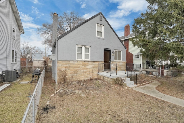 view of front of house with central AC and a front yard