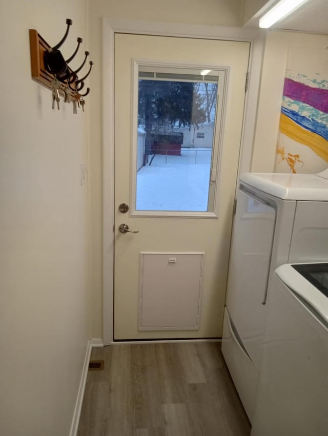 entryway with wood-type flooring and washer and dryer