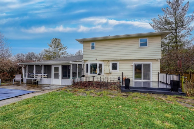 rear view of property featuring a patio, a sunroom, a yard, and a deck