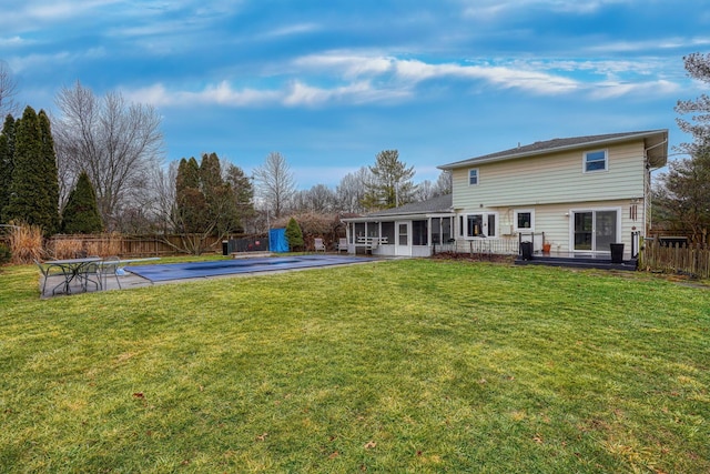 back of house featuring a sunroom, a covered pool, a lawn, and a patio area