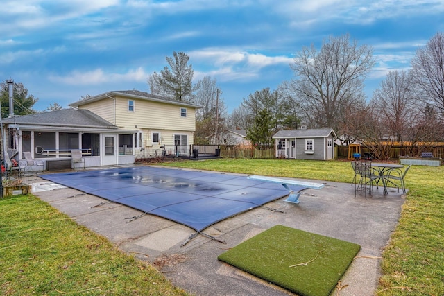 view of swimming pool with a diving board, a lawn, a patio, a storage unit, and a sunroom