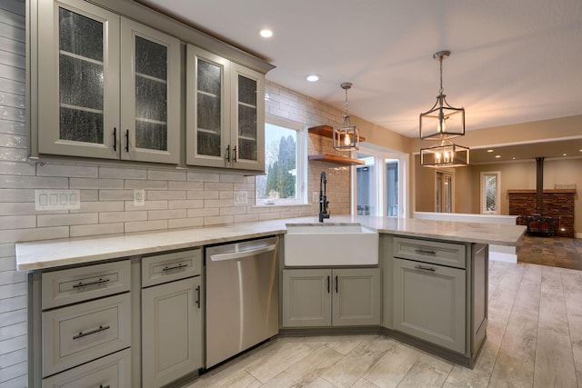 kitchen with light stone counters, dishwasher, sink, and kitchen peninsula