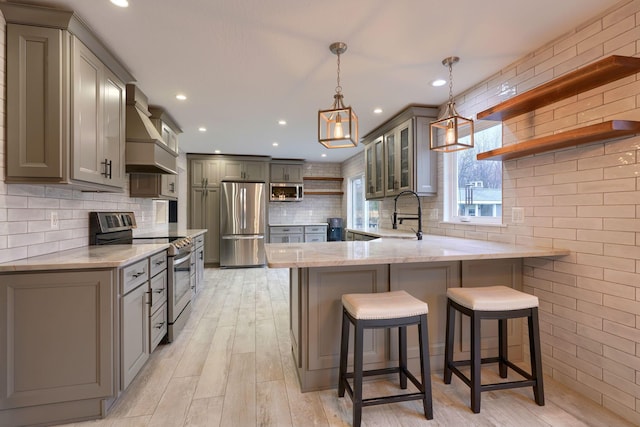 kitchen featuring premium range hood, sink, decorative light fixtures, appliances with stainless steel finishes, and kitchen peninsula