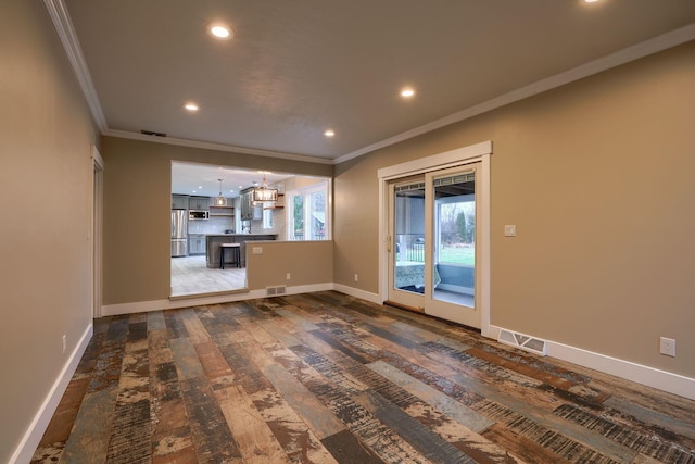 unfurnished living room featuring ornamental molding, dark wood-type flooring, and a chandelier