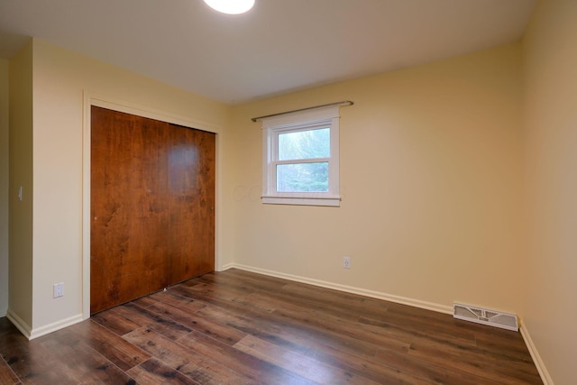 unfurnished bedroom featuring dark wood-type flooring and a closet