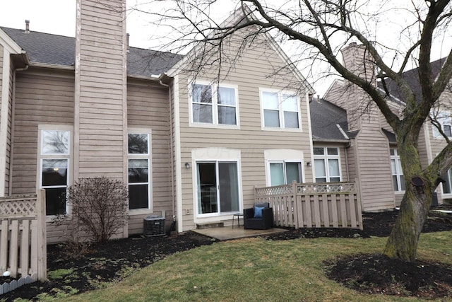 rear view of property featuring central AC and a lawn