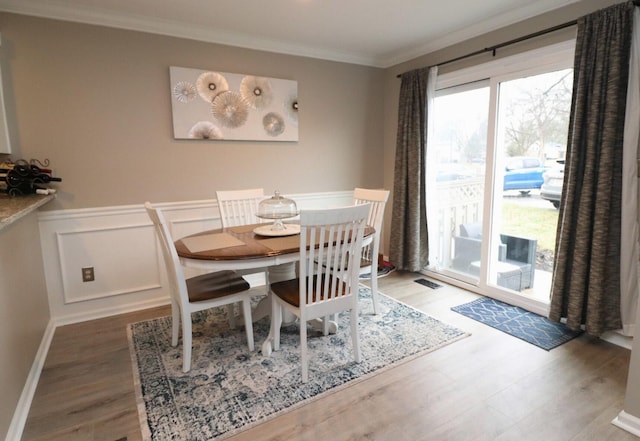 dining area with hardwood / wood-style flooring and ornamental molding