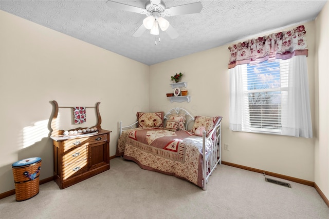 carpeted bedroom featuring ceiling fan and a textured ceiling