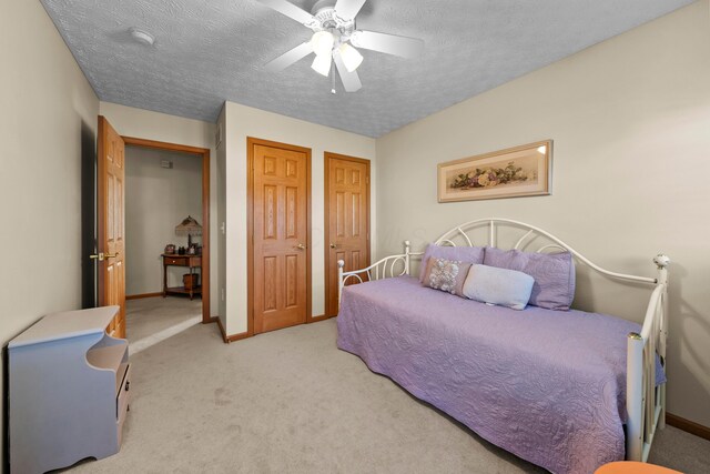 bedroom with light carpet, ceiling fan, a closet, and a textured ceiling