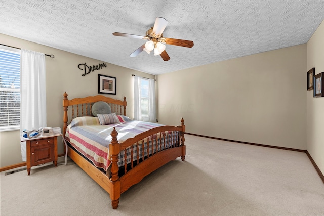 bedroom featuring light carpet, a textured ceiling, and ceiling fan