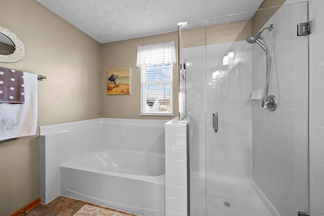 bathroom featuring a textured ceiling and separate shower and tub