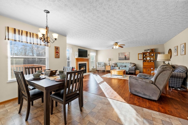 dining room with ceiling fan with notable chandelier and a textured ceiling