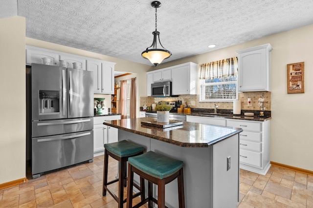 kitchen with a wealth of natural light, a center island, white cabinets, and appliances with stainless steel finishes